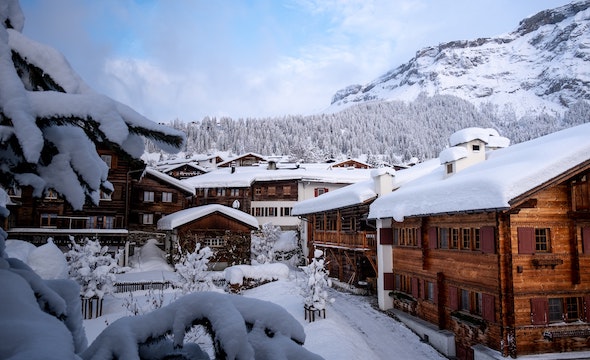A cozy, snow-covered wooden chalet in a winter village scene.